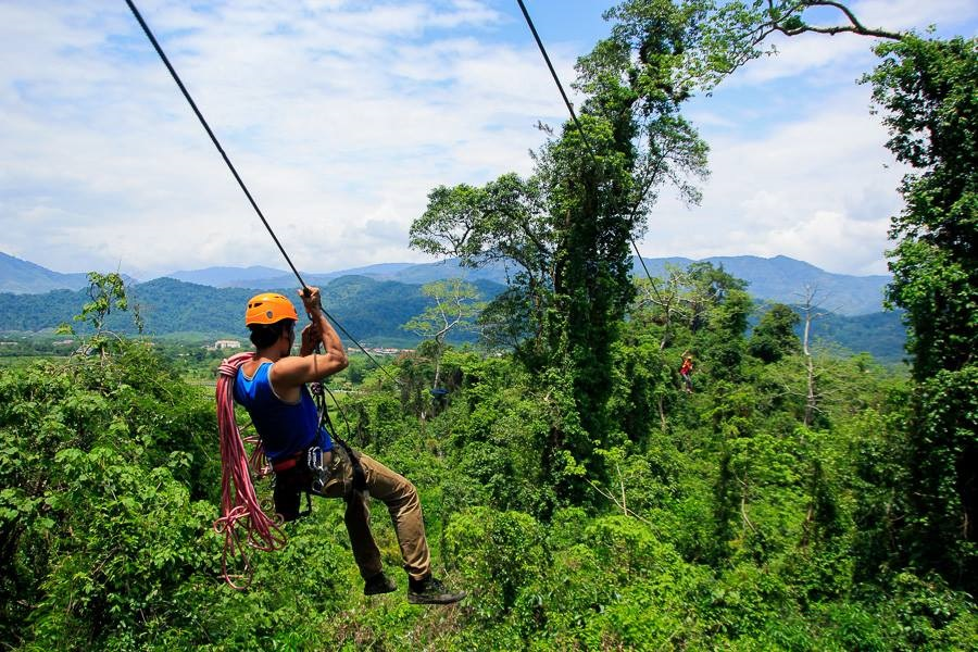 a man zip lining through the forest